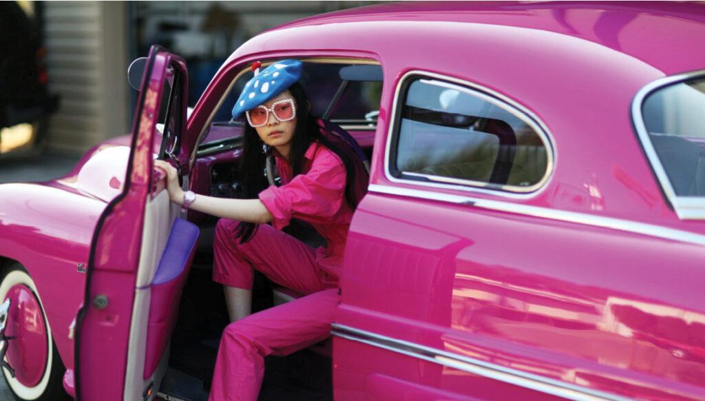 A woman dressed in a pink dress gets out of a pink car