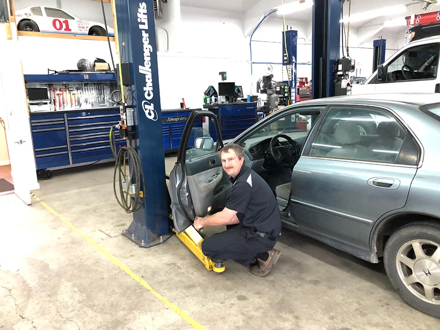 Mechanic working on car in shop.