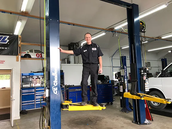 Mechanic standing on repair shop gear.