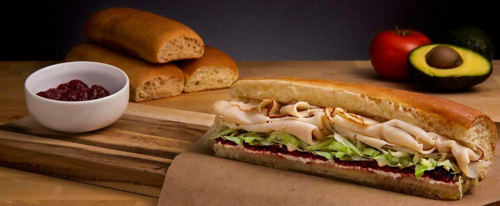 A hero sandwich sits on a wood frame