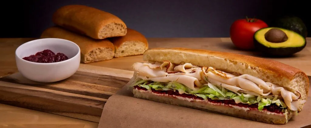 A hero sandwich sits on a wood frame
