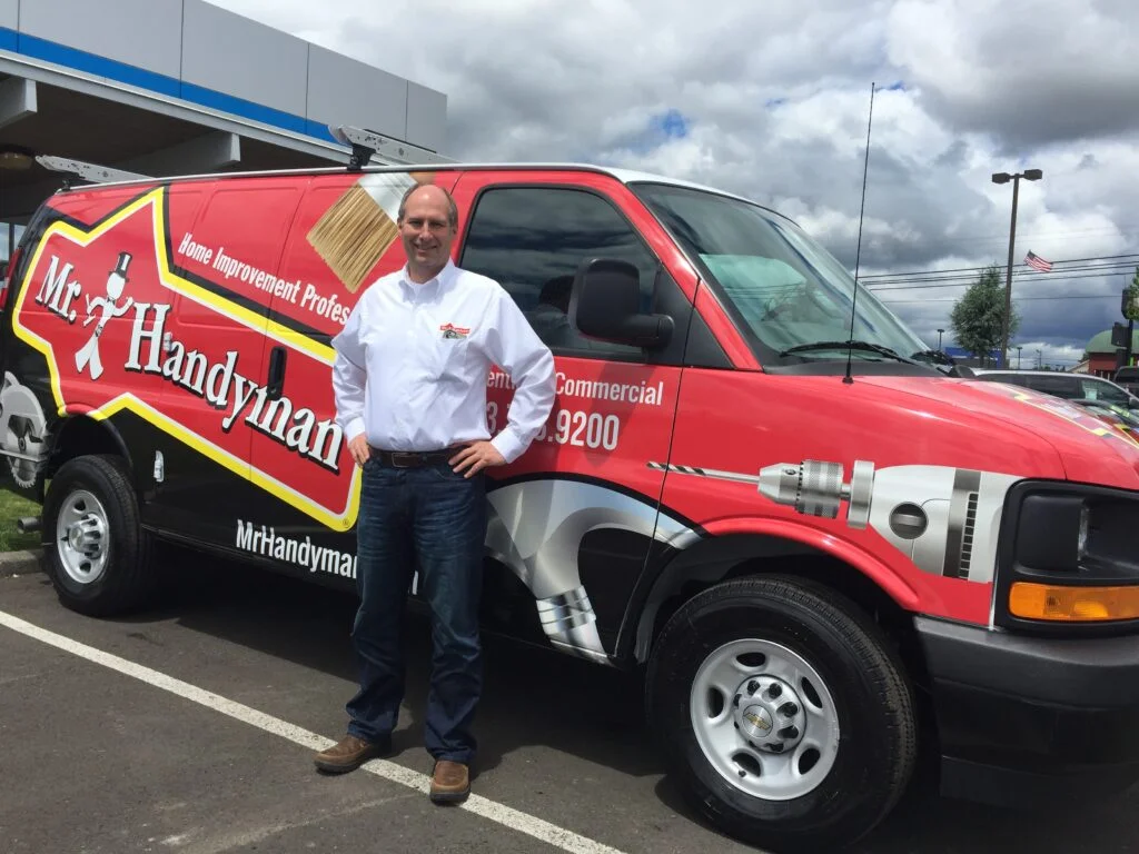 Weatherproofing technician stands next to his truck