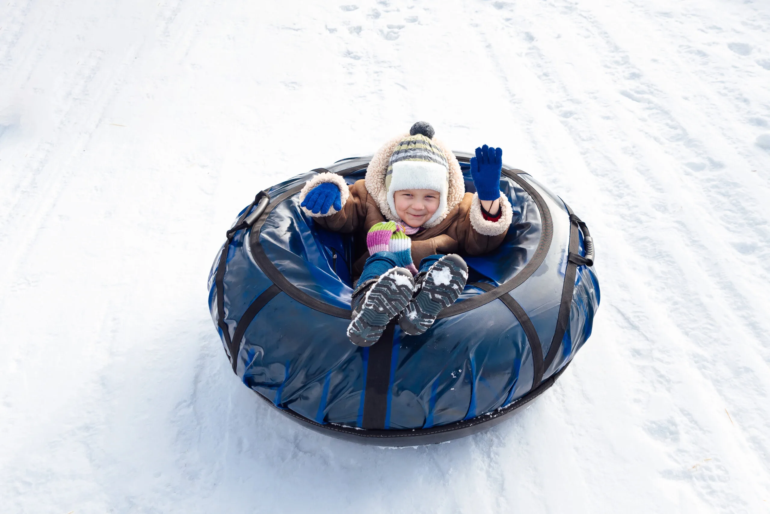 A happy child sits in a snow inner tube