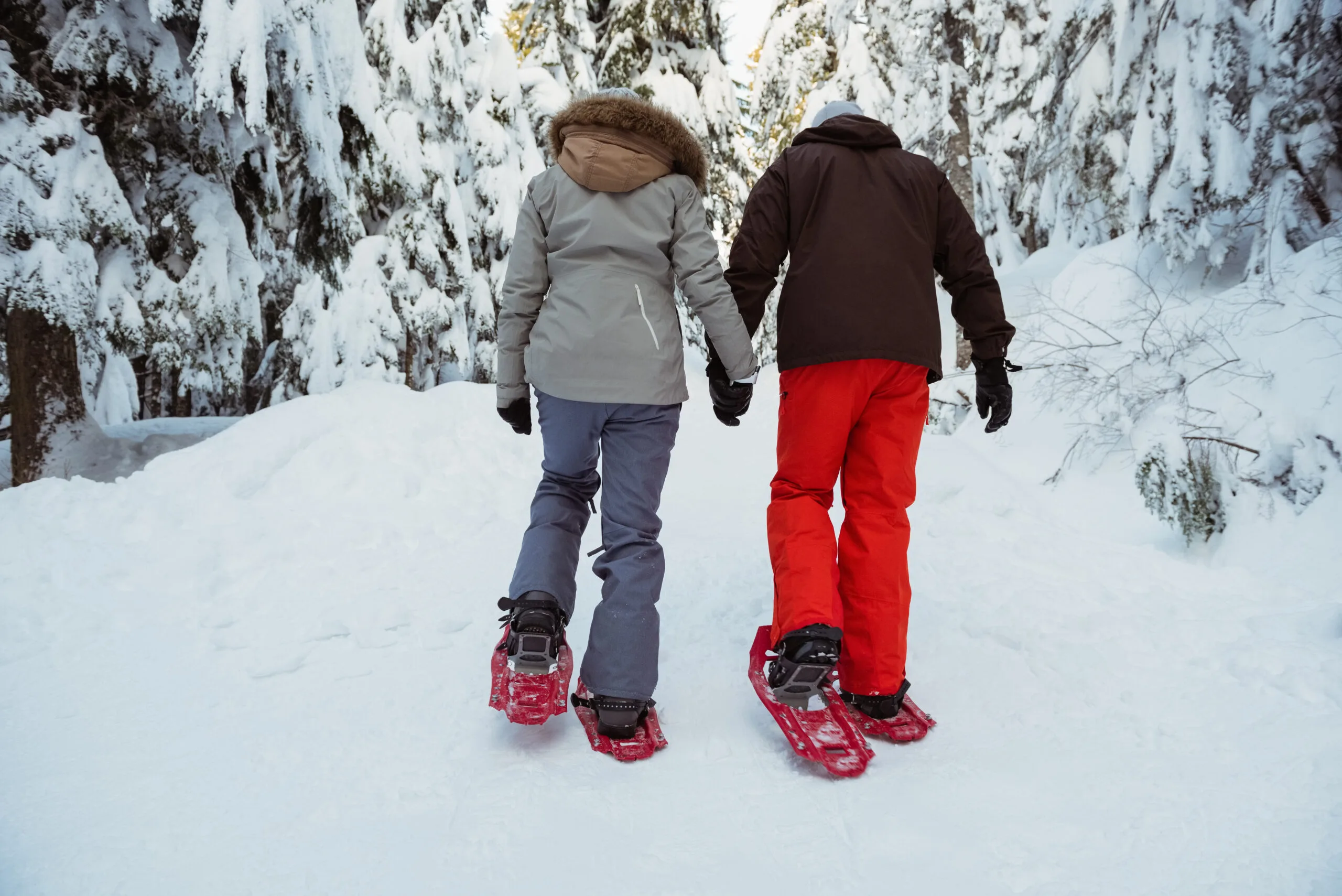 A couple walks through the snow with snowshoes